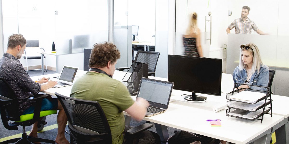 People working at coworking desk with laptops
