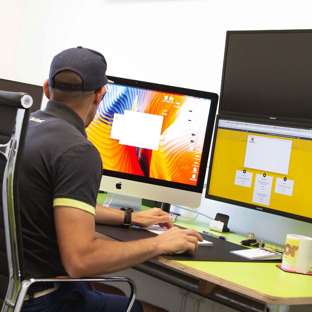 Member working at desk with 3 large screens and coffee mug